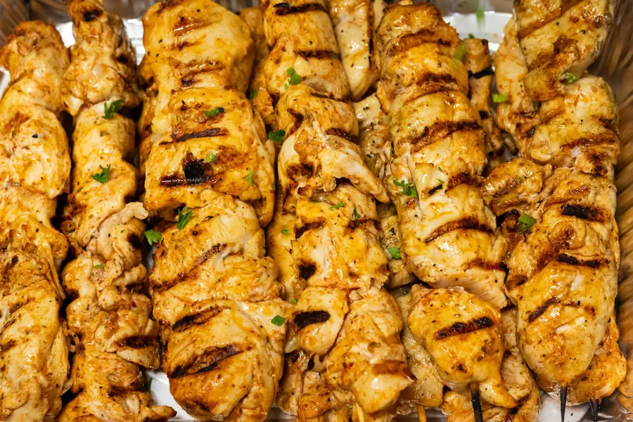 Tray of grilled chicken skewers finished with fresh parsley