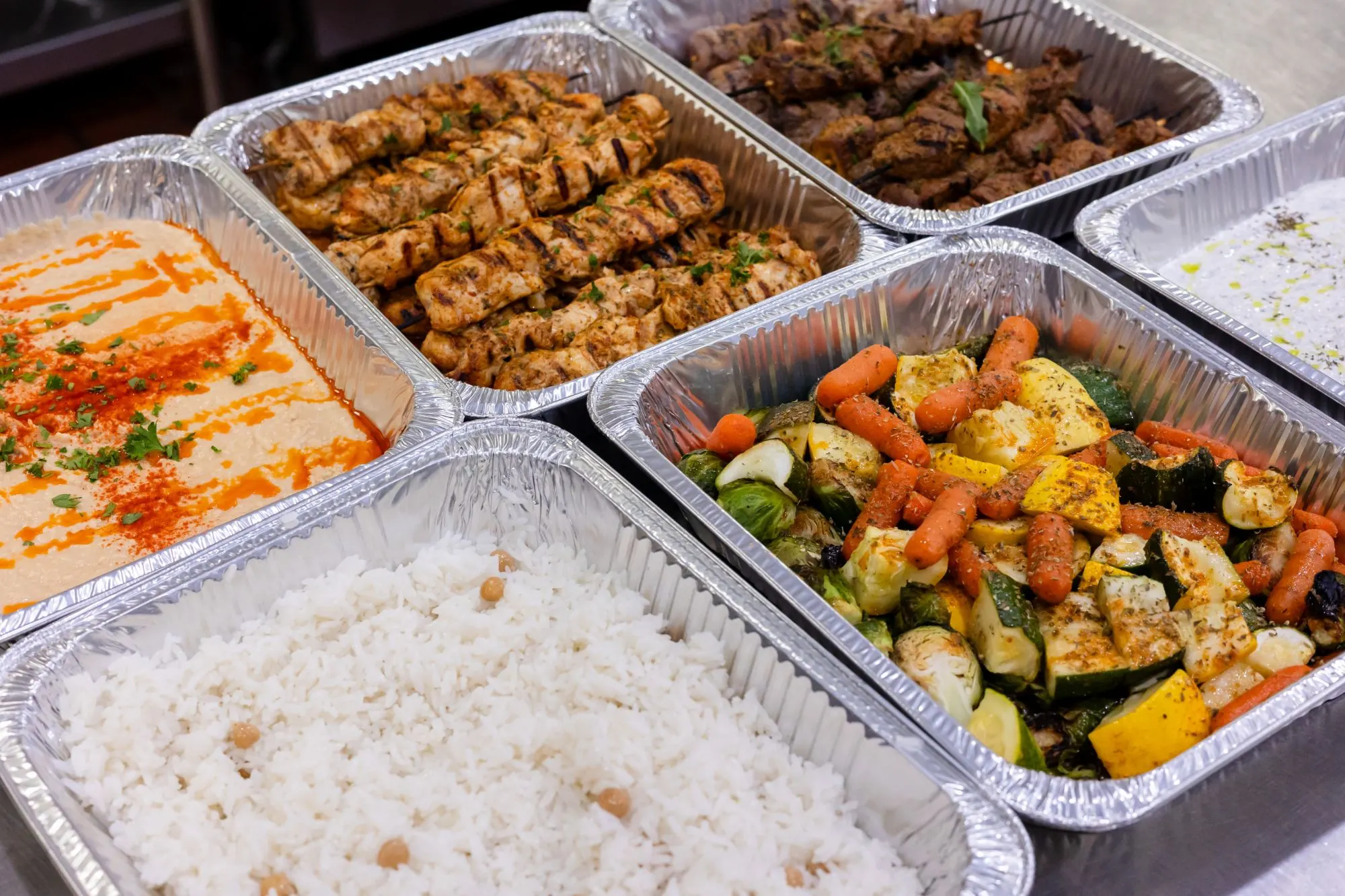 Kalimera Mediterranean catering trays with hummus, chicken and meat skewers, chickpea rice, roasted vegetables and tzatziki