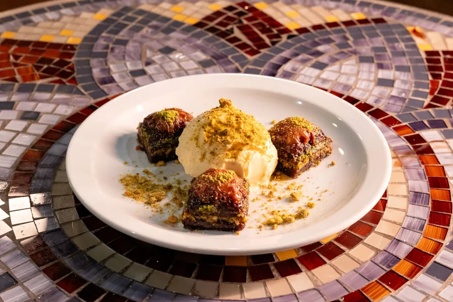 Three pieces of baklava with a scoop of ice cream and crushed pistachio