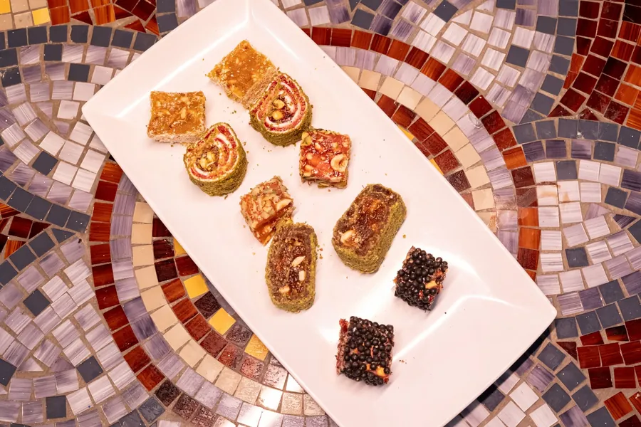White platter of assorted Turkish sweets rolled in pistachio and topped with nuts
